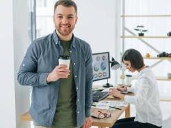 Positive male manager standing in front of table where employee is working
